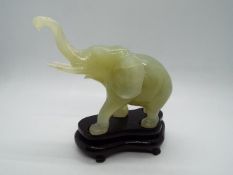A Chinese, celadon green, bowenite carving of an elephant with raised trunk,