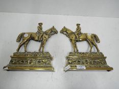 A pair of brass door stops in the form of horse riders,