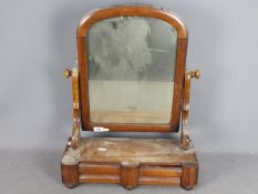 A Victorian toilet mirror with twin drawers to the base and raised on bun feet,