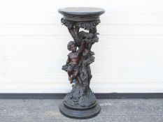 A decorative jardiniere stand of naturalistic form depicting a putto sat in a tree feeding a