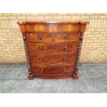 A flame mahogany veneered chest of drawers, bow front and flanked by barley twist columns,