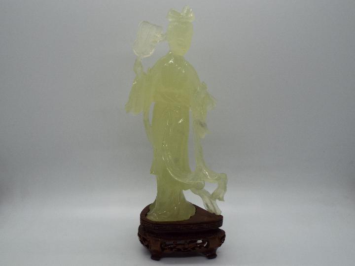 A Chinese, celadon green, bowenite carving of a lady in flowing robes holding a fan,