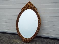 An ornately framed, bevel edge wall mirror, approximately 95 cm x 56 cm.