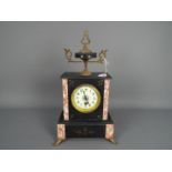 An early 20th century French black and pink marble mantel clock surmounted by a black marble and