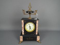 An early 20th century French black and pink marble mantel clock surmounted by a black marble and