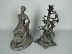 A plaster sculpture of a seated lady and a cast metal figural candle holder,