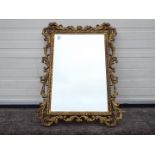 An ornately framed, bevel edge wall mirror, approximately 100 cm x 75 cm.