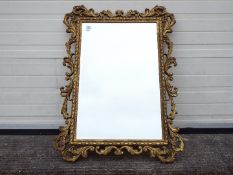 An ornately framed, bevel edge wall mirror, approximately 100 cm x 75 cm.