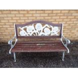 A cast iron and wood slat garden bench with sunflower design to the backrest,