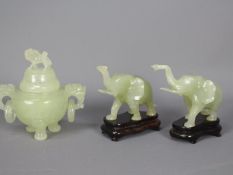 A pair of Chinese, celadon green, bowenite carvings of elephants with raised trunks,