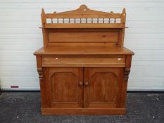 A pine sideboard with twin door cupboard below frieze drawer,