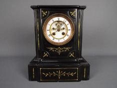 A late 19th century French black slate mantel clock with contrasting incised gold decoration,