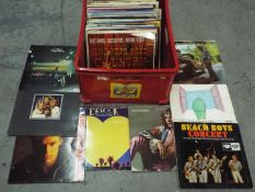 A box of 12" vinyl records to include Dr Hook, Peter Frampton, Genesis, Beach Boys, Bryan Adams,