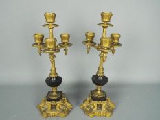 A pair of metal candlesticks, each for four lights, originally part of a garniture,