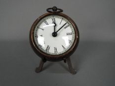 A small, antique style desk clock in the form of a pocket watch, with stand,