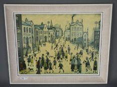 A framed print after L S Lowry, A Village Square, approximately 44 cm x 59 cm image size.