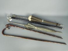 Three walking sticks, one with silver mounts, Birmingham assay 1917 and two parasols.