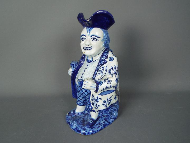 LOT WITHDRAWN - A Delft style blue and white toby jug modelled as a standing man with glass and