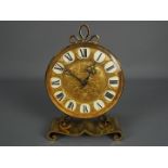 A vintage brass mantel clock by Imhof, raised on scrolled supports, approximately 24 cm (h).