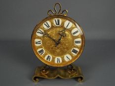 A vintage brass mantel clock by Imhof, raised on scrolled supports, approximately 24 cm (h).