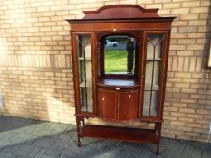 An Edwardian display cabinet with central recessed mirror section above a twin door cupboard,