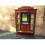 An Edwardian display cabinet with central recessed mirror section above a twin door cupboard,