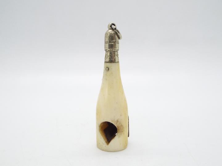 A late Victorian ivory and white metal novelty cigar cutter in the form of a champagne bottle,
