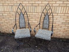 A pair of wrought iron chairs with lancet top back rests and leopard print upholstery.