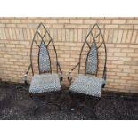 A pair of wrought iron chairs with lancet top back rests and leopard print upholstery.