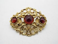 A 14ct gold openwork scroll brooch set with three red cabochons, approximately 12 grams all in.