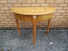 A pine demi lune console table measuring approximately 72 cm x 86 cm x 43 cm.