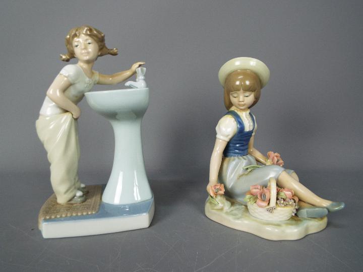 Lladro - Two figurines to include Clean Up Time # 4838 and a seated girl with a basket of flowers,