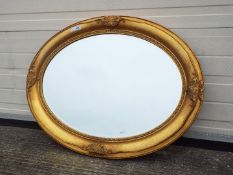 An oval framed, bevel edge wall mirror, approximately 88 cm x 67 cm.