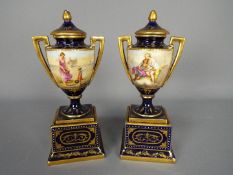 A pair of Vienna style, porcelain twin handled urns and covers decorated with classical scenes,