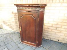 An antique hanging corner cupboard with