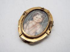 A yellow metal photograph brooch / pendant (pin lacking), approximately 5.5 cm x 4.3 cm and 20.