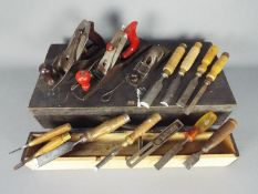 A carpenter's wooden tool case containing a quantity of vintage planes and chisels.