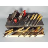 A carpenter's wooden tool case containing a quantity of vintage planes and chisels.