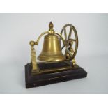 A brass desktop or counter top bell on wooden stand,