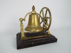 A brass desktop or counter top bell on wooden stand,