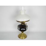 A brass oil lamp with ceramic reservoir and milk glass shade,