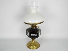 A brass oil lamp with ceramic reservoir and milk glass shade,