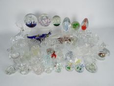 A collection of various glassware to include paperweights, vases, candlesticks / candle holders,