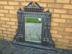 A cast iron framed overmantel mirror of architectural form with bevelled pane,
