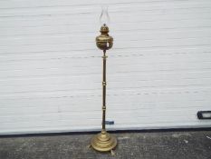 A floor standing, telescopic, brass oil lamp, approximately 144 cm (h) when at lowest setting.