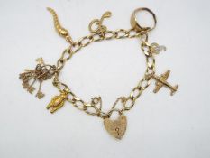 A 9ct gold charm bracelet with safety chain, with a quantity of 9ct charms, 20 cm length,