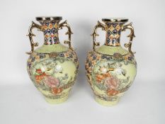 A pair of twin handled Japanese vases decorated with panels of birds and flowers,
