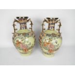 A pair of twin handled Japanese vases decorated with panels of birds and flowers,