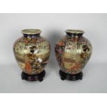 A pair of Japanese vases of ovoid form decorated with panels of a well dressed lady in a garden