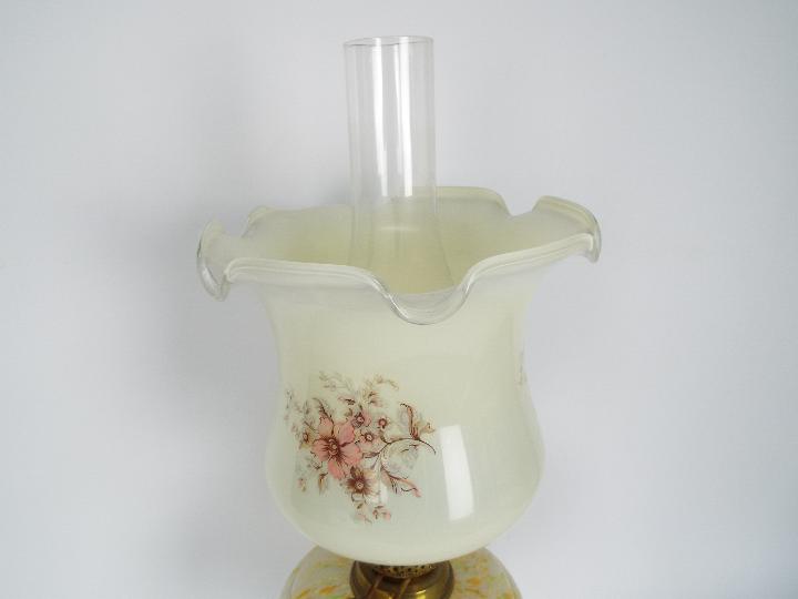 An oil lamp with black ceramic base and brass support below a mottled glass reservoir and floral - Image 2 of 4